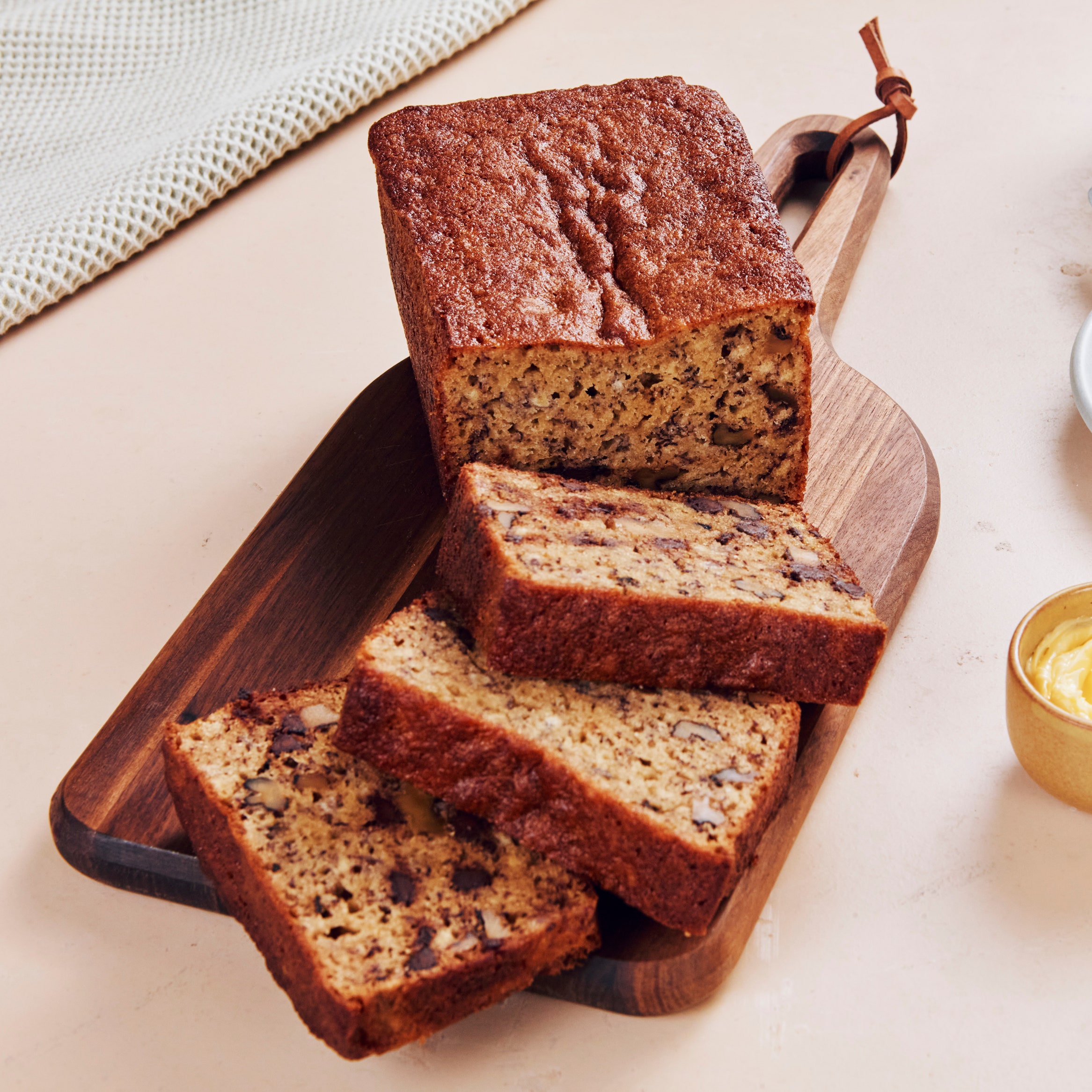 A loaf of chocolate chip banana bread on a cutting board with three slices cut.