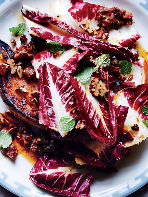 A halved potato, deeply caramelized and topped with red lettuces, mint, and a pecan vinaigrette.