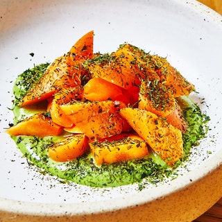 Carrot crudite over shishito pepper pistachio dip topped with nori powder in a white bowl.