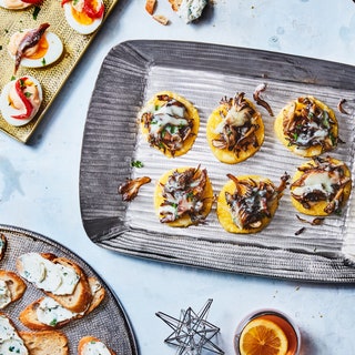 A plate of crispy polenta bites with wild mushroom ragout surrounded by ornaments jammy eggs and crostini—classic New...